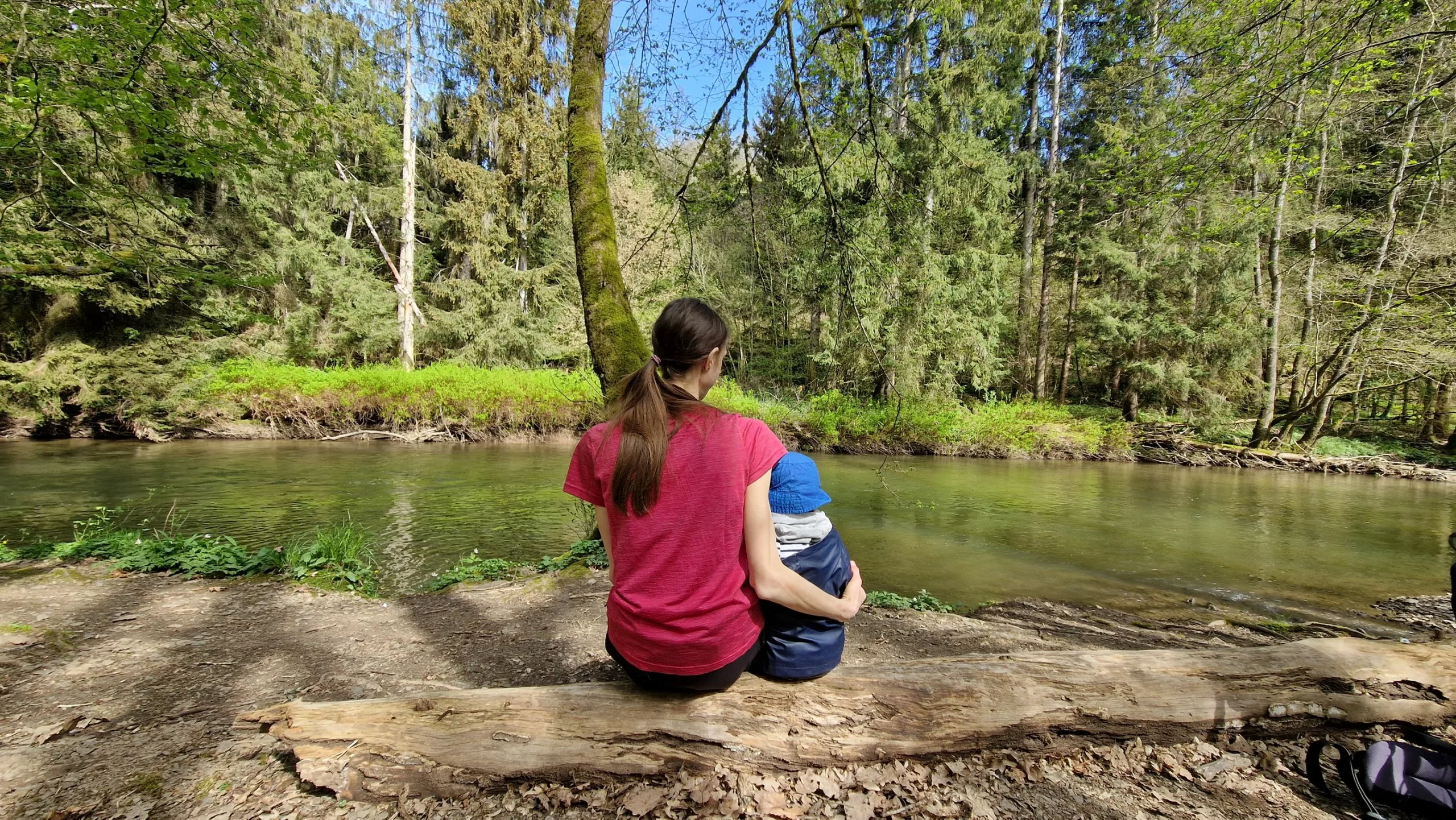 Svenja und Sohn auf einem Baumstamm am Ufer der Lieser
